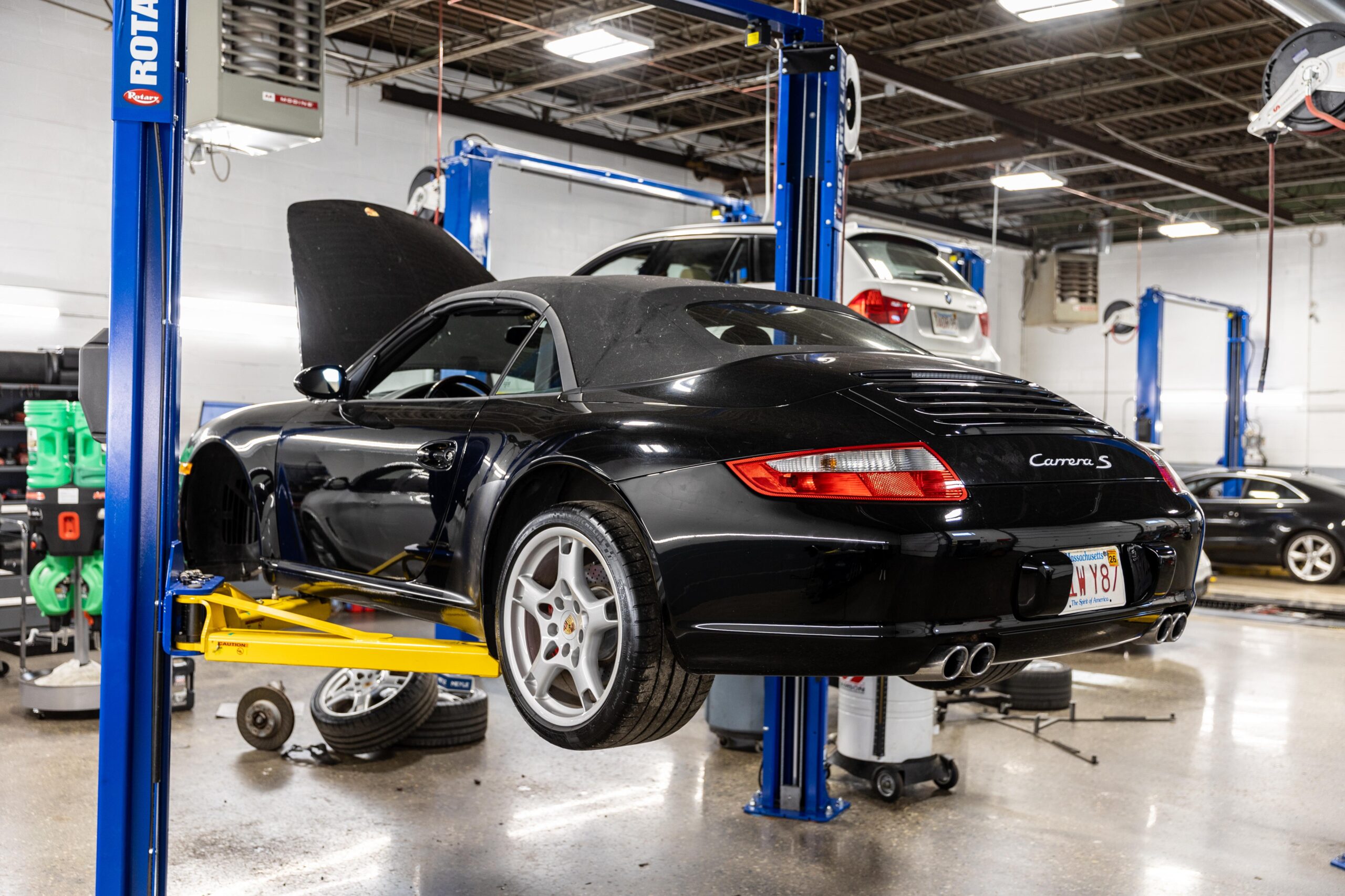 A sleek black Porsche Carrera S sits on a hydraulic lift in North Shore Motor Werks european auto repair shop specialist.